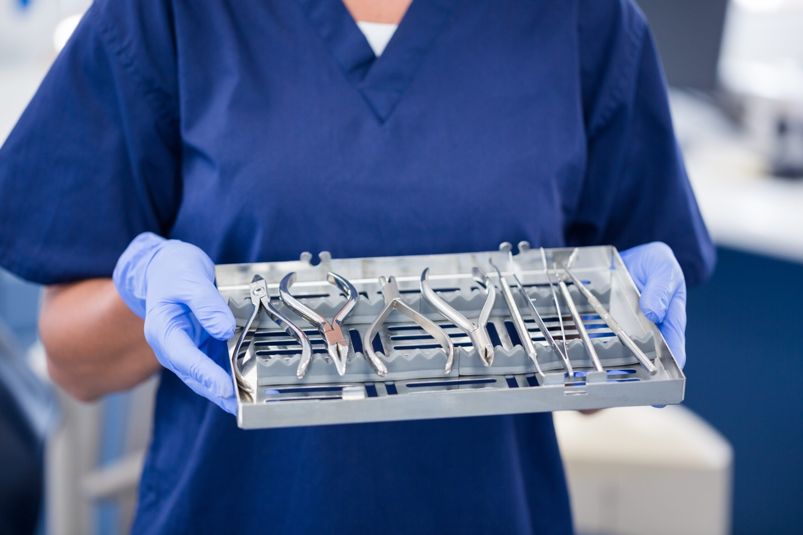 Dentist in blue scrubs holding tray of tools at the dental clinic dental equipment